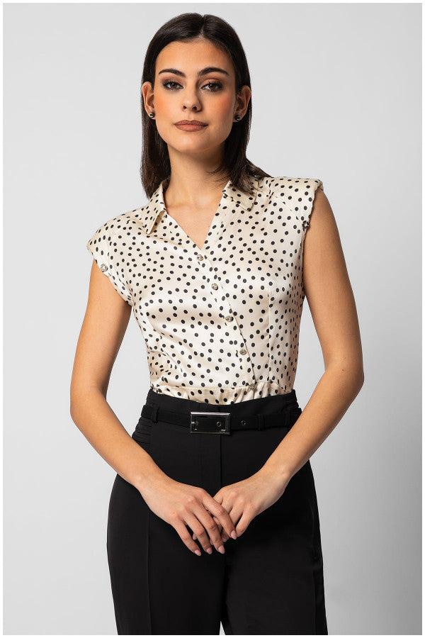 Woman wearing sleeveless satin elegant blouse with black polka dots and decorative buttons paired with black tailored pants