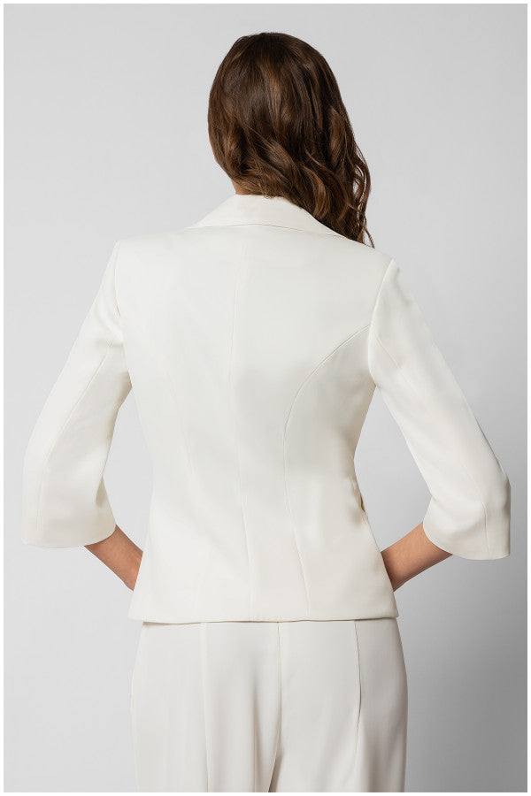 Back view of a fitted white tailored blazer with three-quarter sleeves on a woman with wavy hair