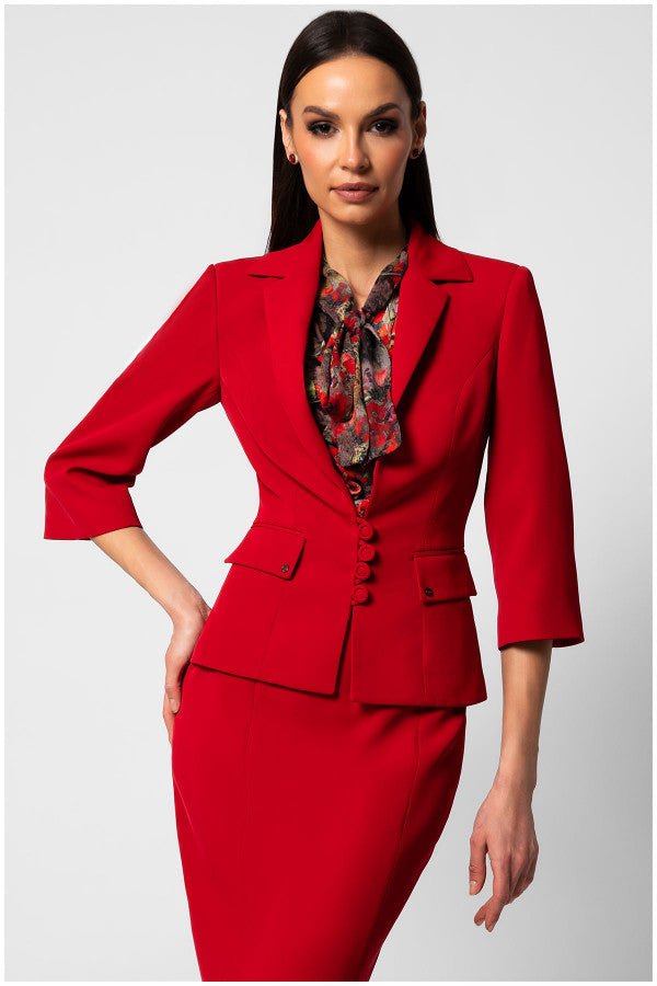 Woman wearing a fitted tailored blazer Alexa in signature red with sharp lapels and five-button closure paired with a floral blouse and matching skirt