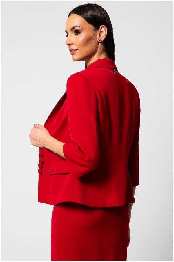 Woman wearing a tailored blazer Alexa in signature red with sharp lapel collar and three-quarter sleeves, shown from the back.