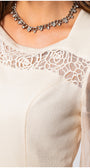 Close-up of a beige lace-trimmed top with a necklace. Luna Fashion House