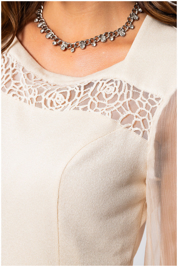 Close-up of a beige lace-trimmed top with a necklace. Luna Fashion House