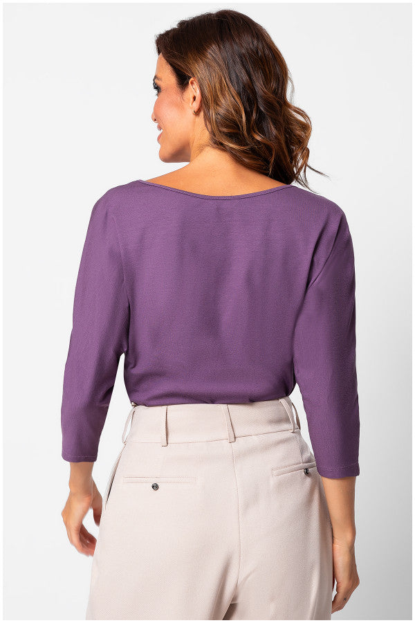 Woman wearing a purple blouse and beige pants on a white background Luna Fashion House
