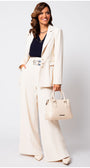 Woman in an ivory Luna Fashion House suit holding a beige handbag against a light gray background