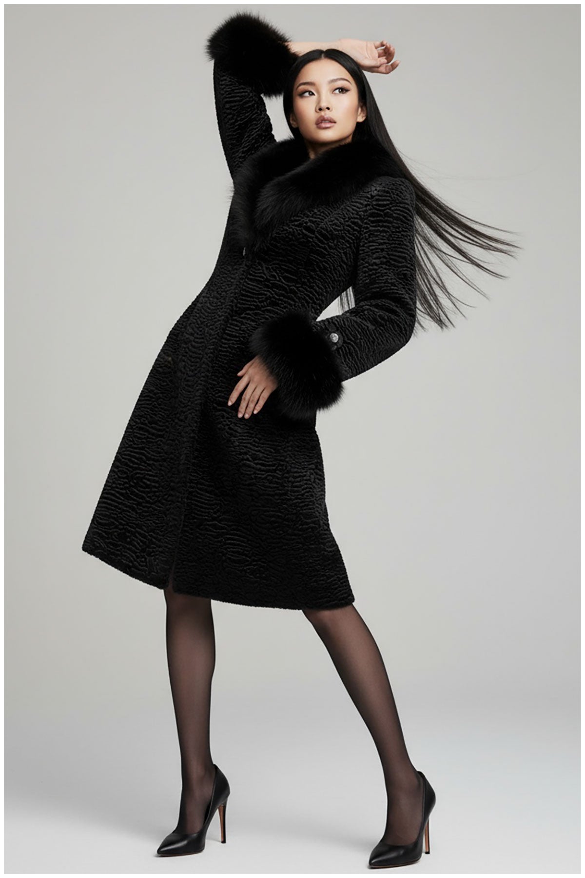 Woman wearing a black coat with fur trim on a white background