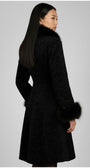 Woman wearing a black textured coat with fur trim on a gray background
