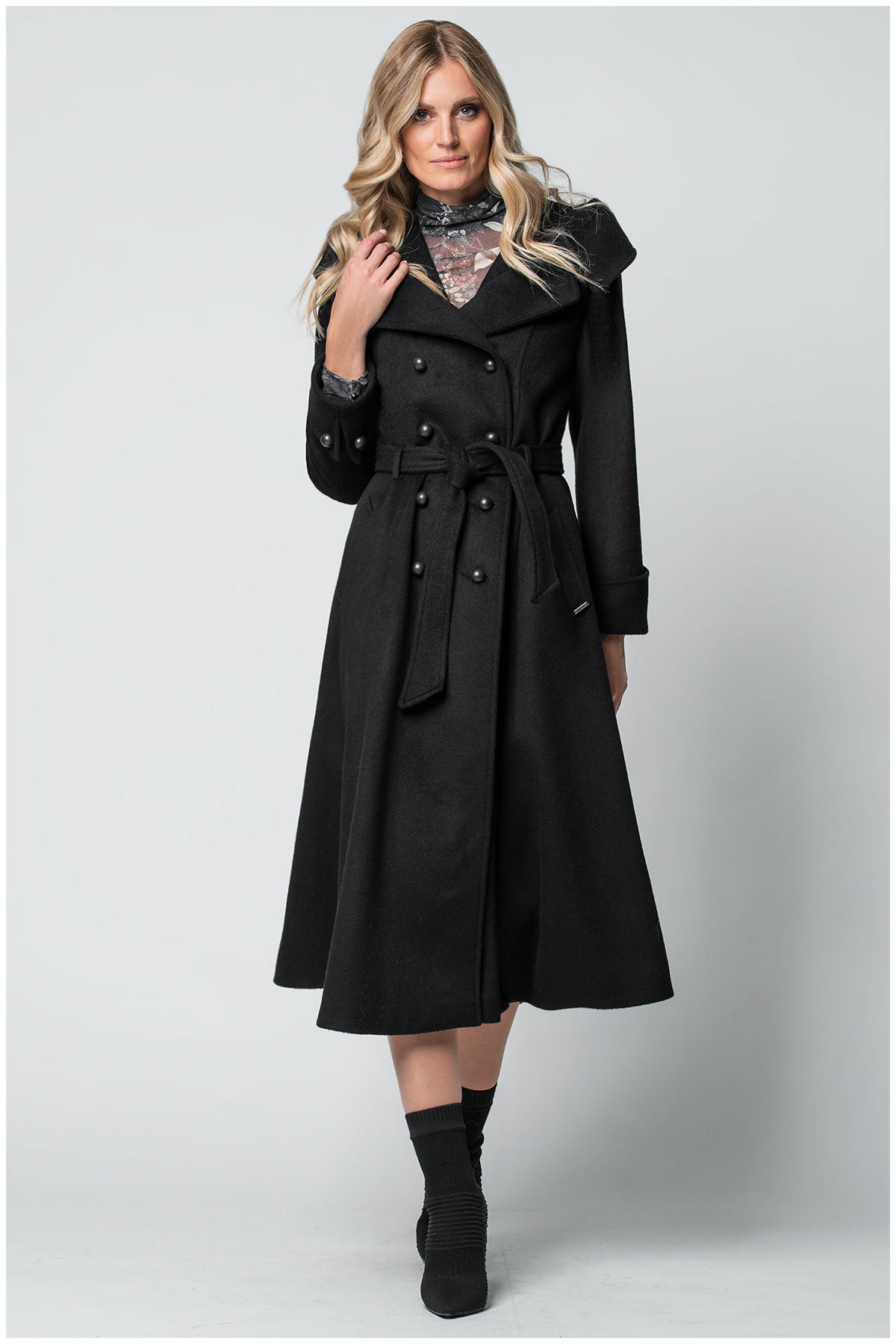 Woman wearing a black Luna Fashion House coat on a white background