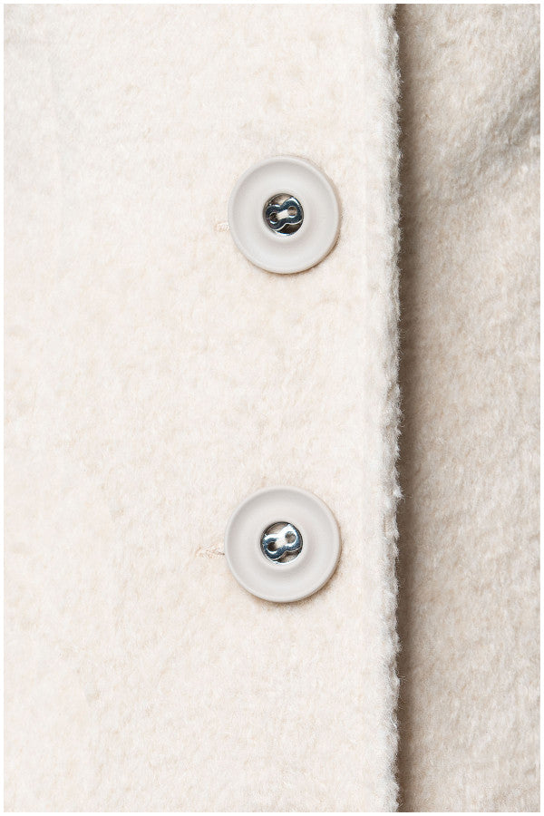 Close-up of a textured fabric surface with buttons on a light background Luna Fashion House