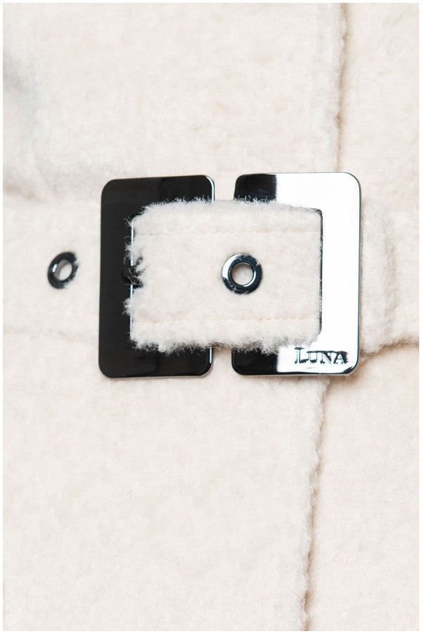 Close-up of a button on a textured fabric surface with 'LUNA' branding. Luna Fashion House