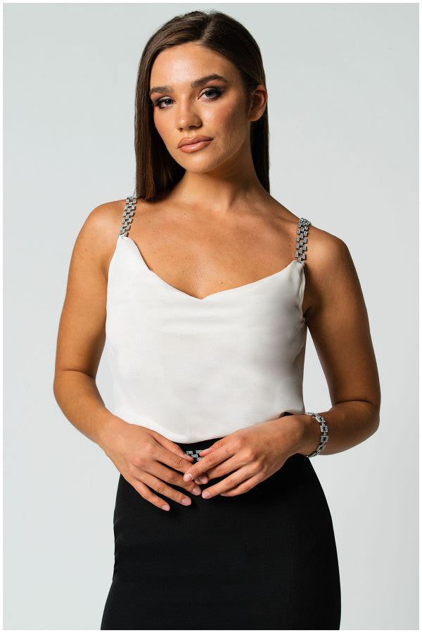 Woman wearing an white elegant blouse Dora with jeweled straps paired with a black skirt against a light background