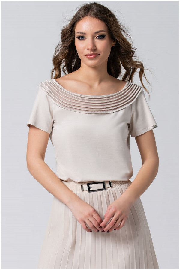 Women wearing ivory Lola business Top with pleated neckline and short sleeves, paired with pleated skirt and belt.