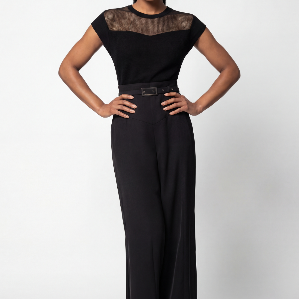 Black wide-leg lace jumpsuit with belted waist styled for a cocktail event against a neutral background