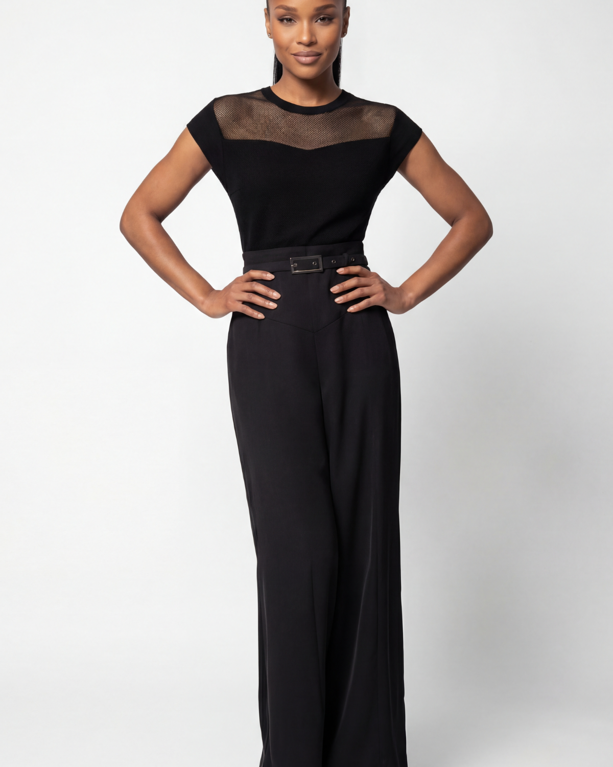 Black wide-leg lace jumpsuit with belted waist styled for a cocktail event against a neutral background