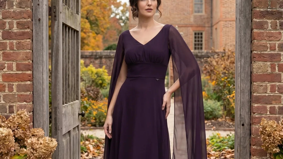 Rebeka long dress in deep plum with long open sheer sleeves, worn under a brick garden archway with autumn trees, pumpkins, and wheat sheaves