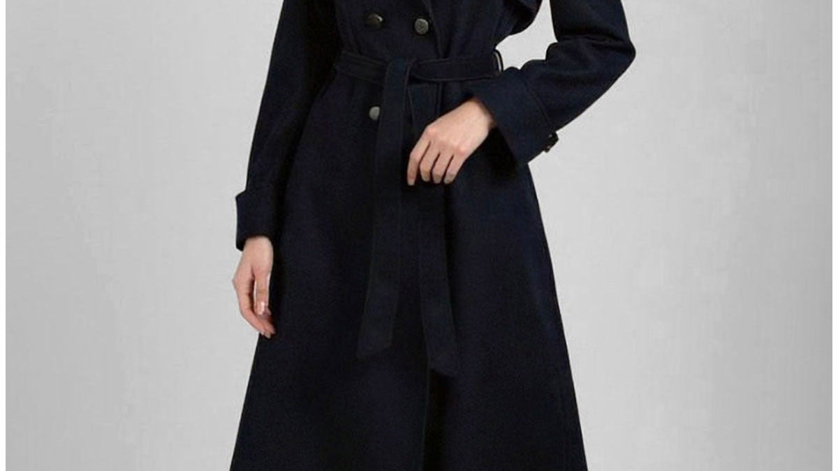 A tall woman in the Navy Wool Trench Coat Clara, belted at the waist, full length hem, notched lapel, deep navy
