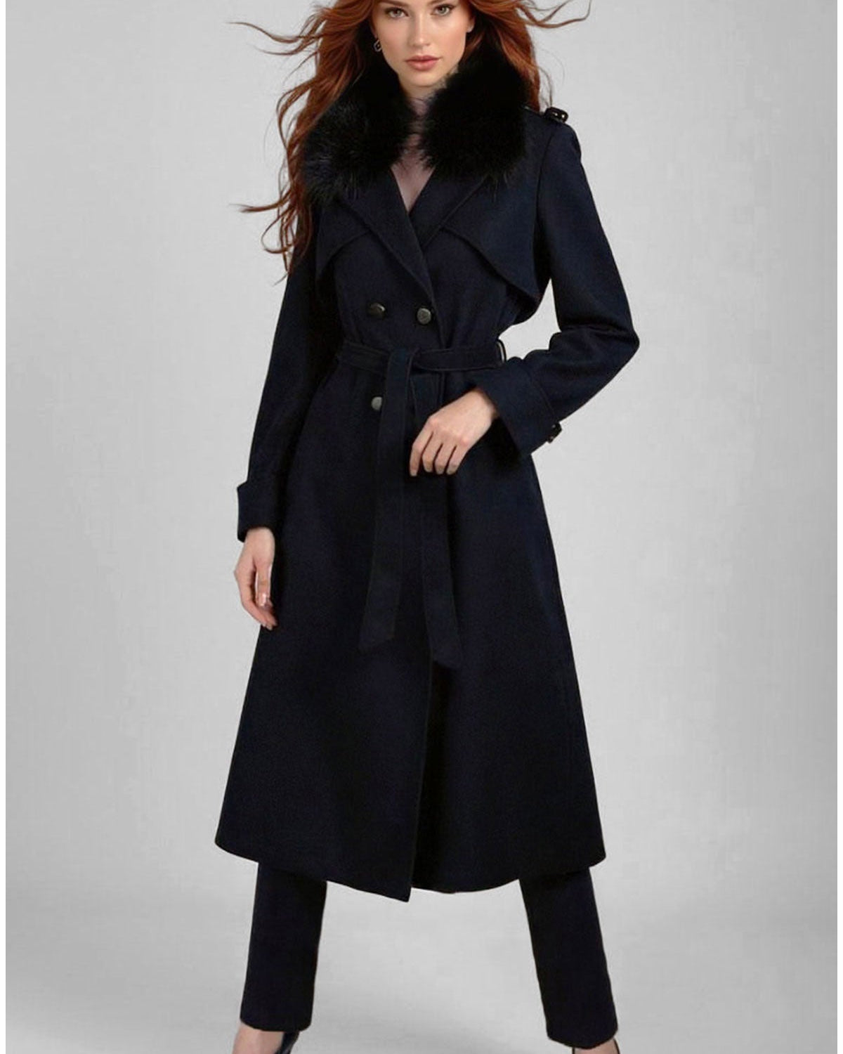 A tailored navy wool trench coat worn over a dark suit by a professional woman standing in a corporate reception area
