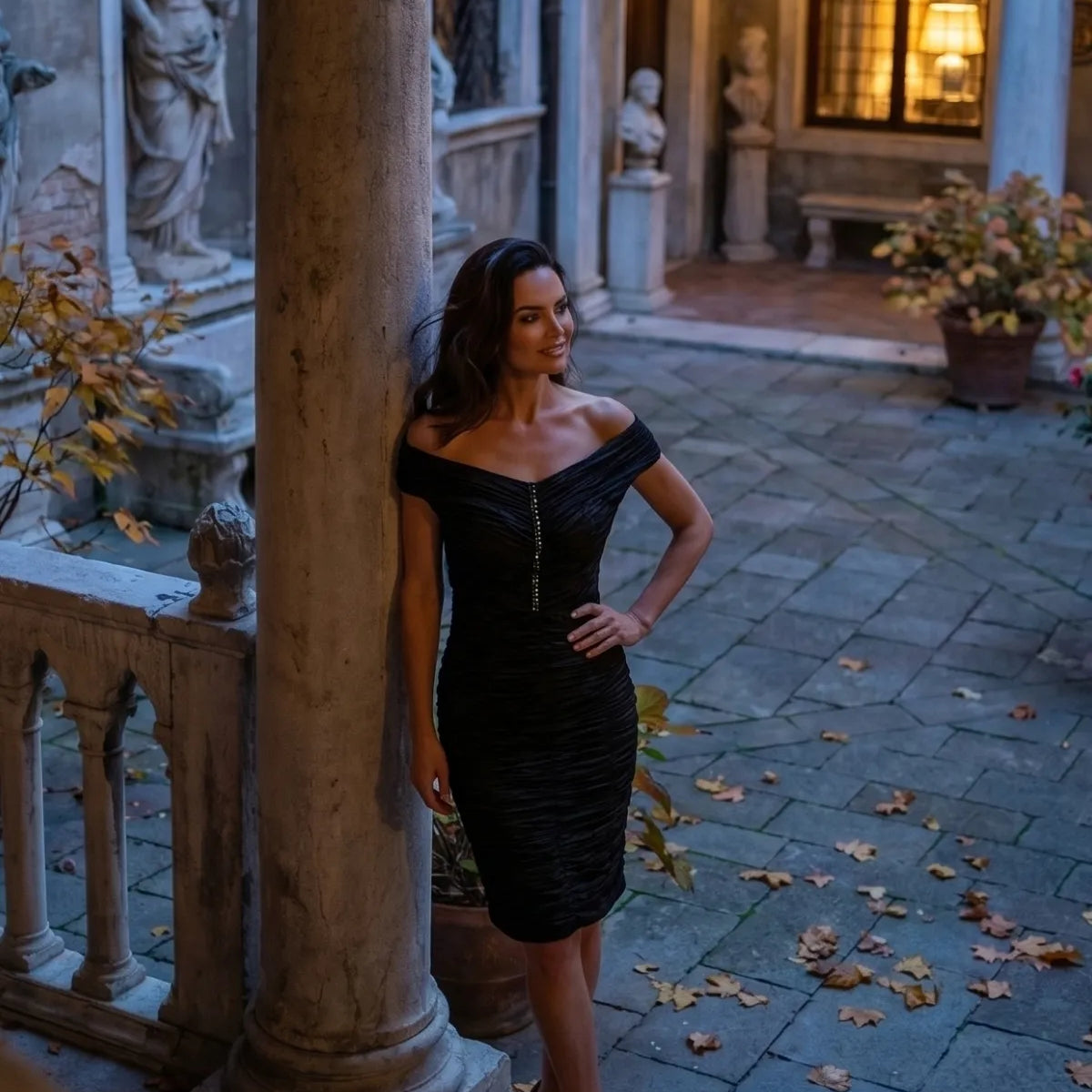 Black off shoulder ruched dress just below the knee, under a stone arch at night