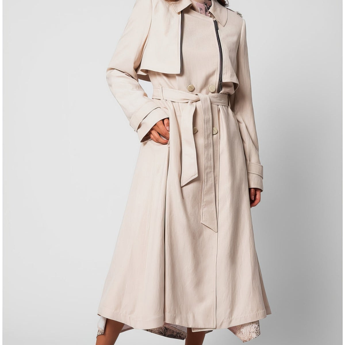 Beige classic long coat with self-fabric belt and full lining worn over ivory wide-leg trousers, transitional season
