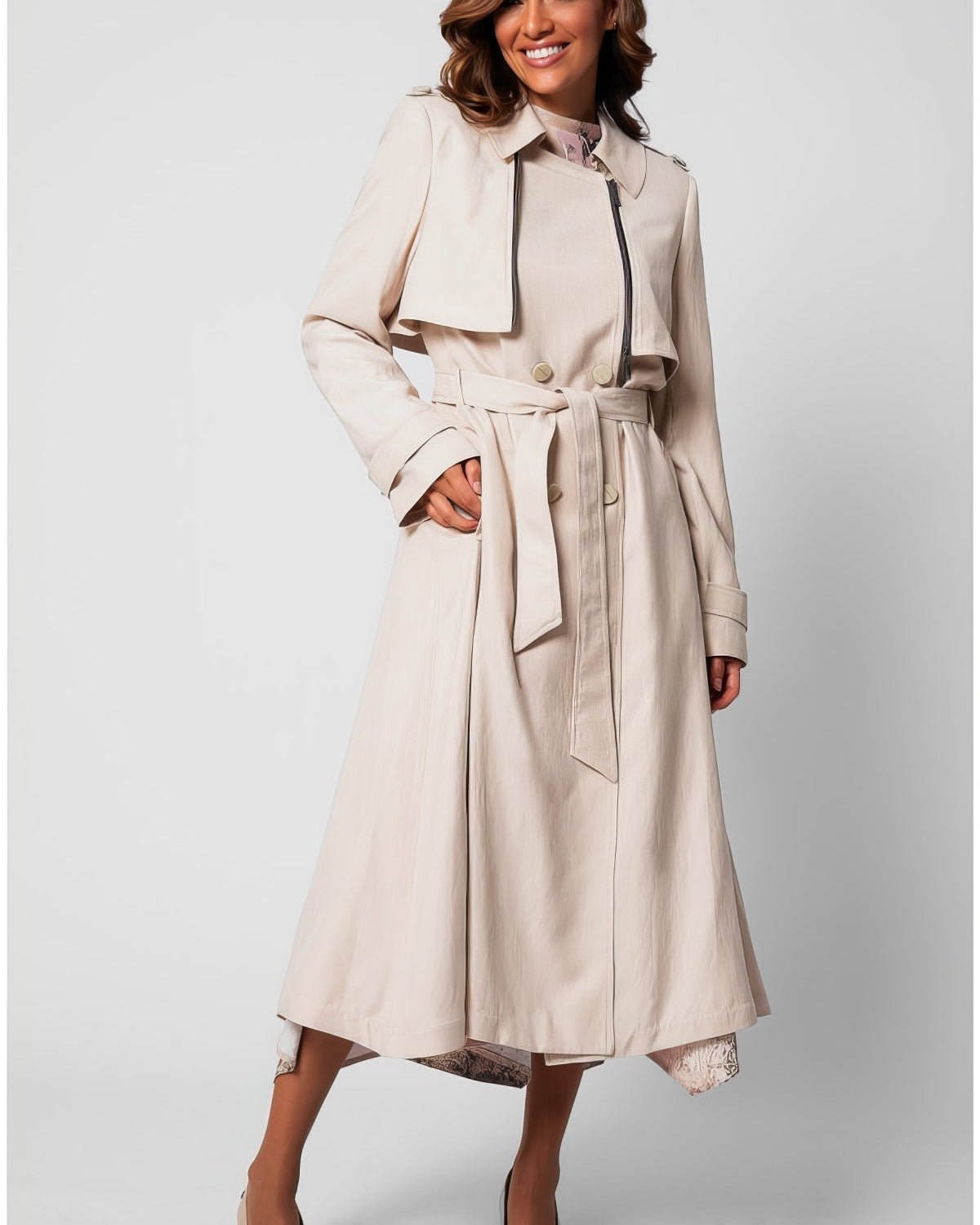 Beige classic long coat with self-fabric belt and full lining worn over ivory wide-leg trousers, transitional season