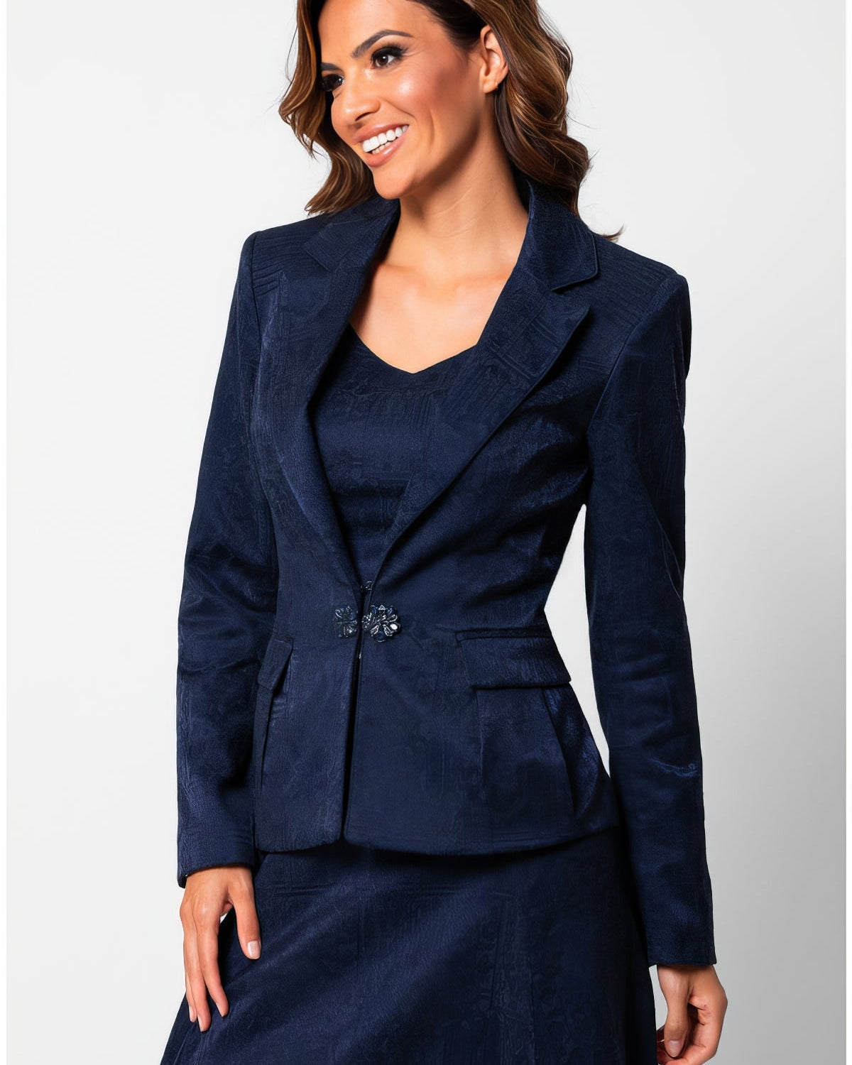 Navy tailored jacquard blazer with sculpted waist and decorative clasp closure, worn against a neutral background