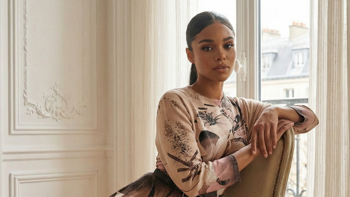 A woman in the Luna Iris A-Line Midi Dress in Blush Floral seated by a tall window