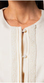 Close-up of tailored blazer Jacket Lola in white showing round neckline and delicate beaded front button detailing.