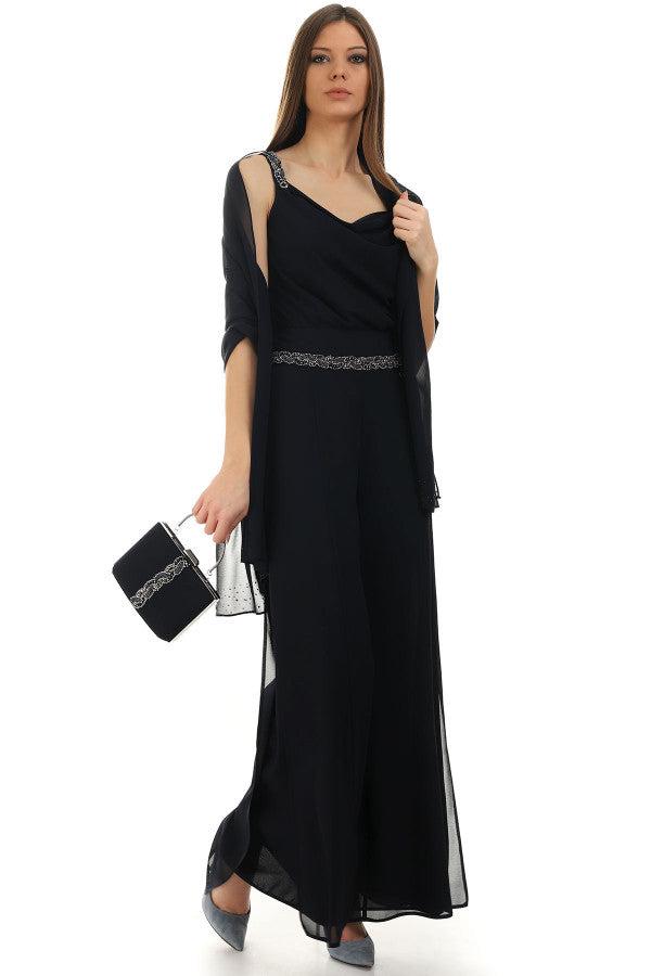 structured handbag woman in elegant black jumpsuit holding Bag Klara evening purse with metallic handle and beaded embellishment