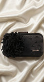 Black evening clutch with feather flower and beadwork styled on cream satin