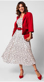 Woman wearing a strapless white elegant midi dress satin midi dress with black polka dots and a red blazer, belt, clutch, and heels.
