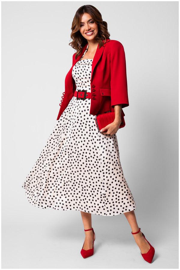 Woman wearing a strapless white elegant midi dress satin midi dress with black polka dots and a red blazer, belt, clutch, and heels.