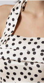 Close-up of Melissa satin white elegant midi dress with black polka dots on ivory fabric and strap detail at shoulder
