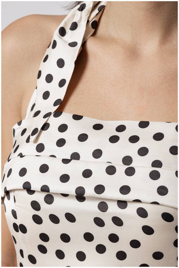 Close-up of Melissa satin white elegant midi dress with black polka dots on ivory fabric and strap detail at shoulder