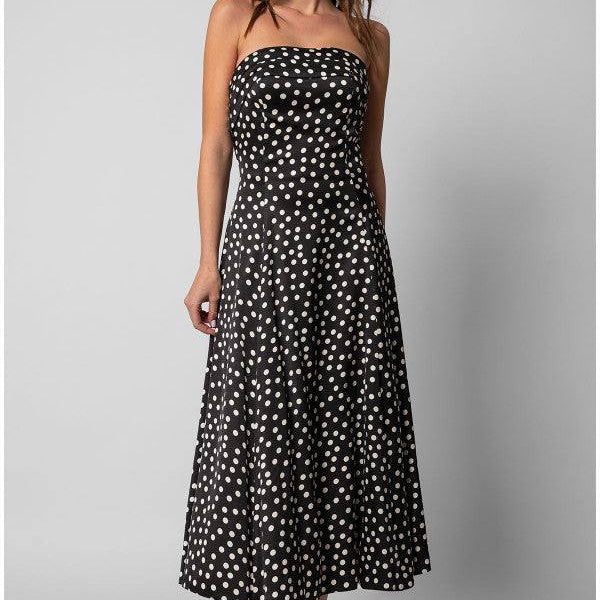 Model wearing a black elegant midi dress black and ivory polka dot strapless satin midi dress with a fitted bodice and flowing skirt