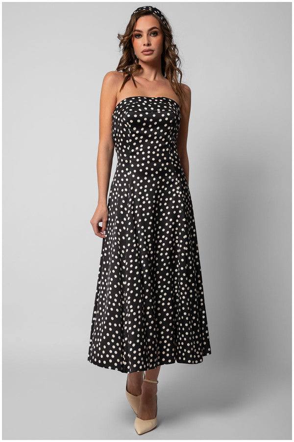 Model wearing a black elegant midi dress black and ivory polka dot strapless satin midi dress with a fitted bodice and flowing skirt