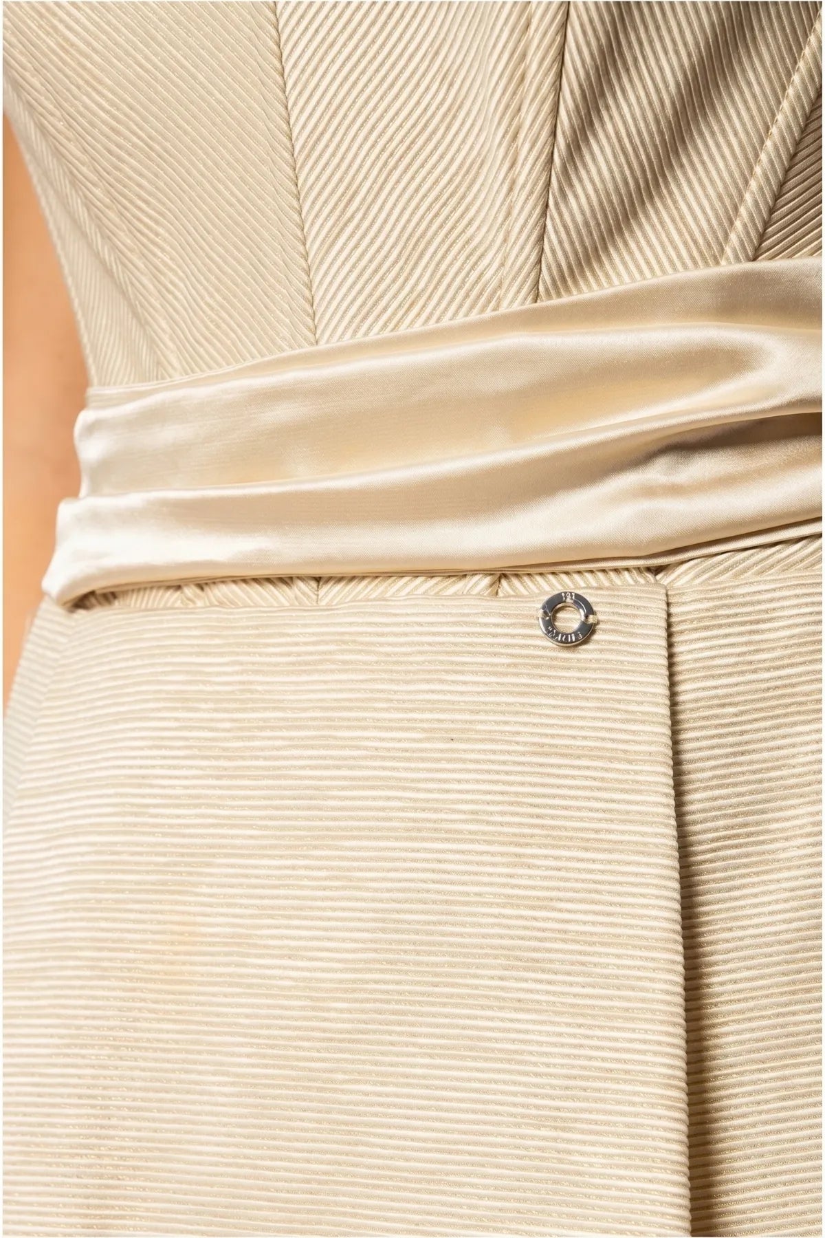Fabric close-up of Melisa beige dress showing ribbed texture, smooth waist sash, and Luna accent.