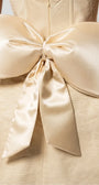 Close detail of Melisa beige mini dress showing the oversized back bow and center zipper.
