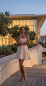 Melisa beige strapless mini dress worn on a modern terrace at dusk with a polished evening feel.