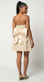 Angled back view of Melisa beige strapless mini dress with large bow and flared skirt.