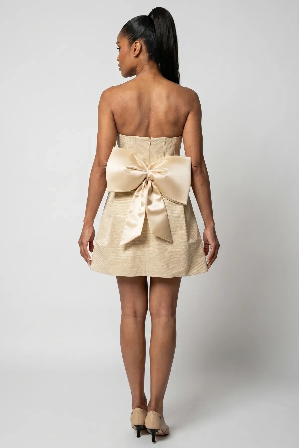 Back view of Melisa beige mini corset dress with center zipper and oversized removable bow.