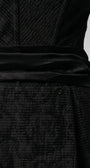 Fabric close-up of Melisa black mini dress showing textured weave, satin waistband, and Luna accent.