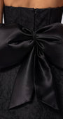 Close detail of Melisa black strapless mini dress showing the oversized removable back bow.