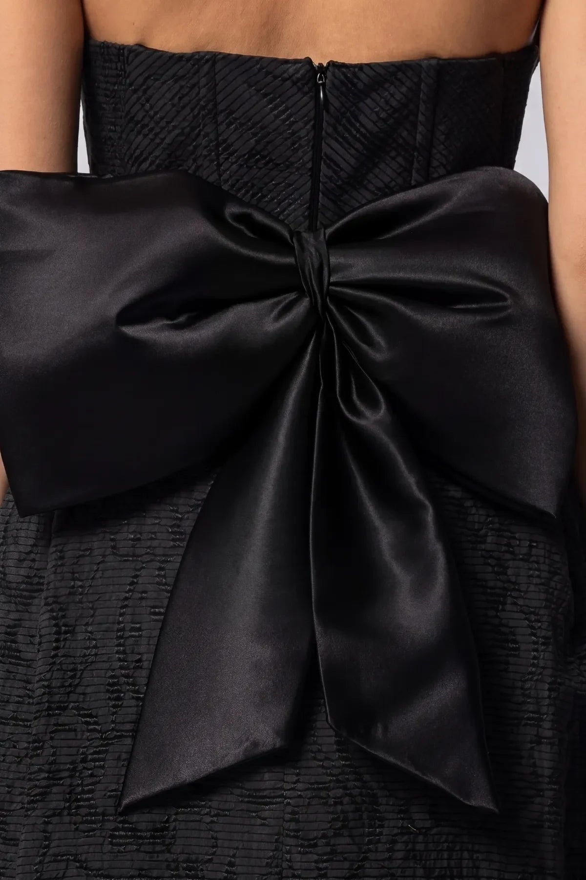 Close detail of Melisa black strapless mini dress showing the oversized removable back bow.
