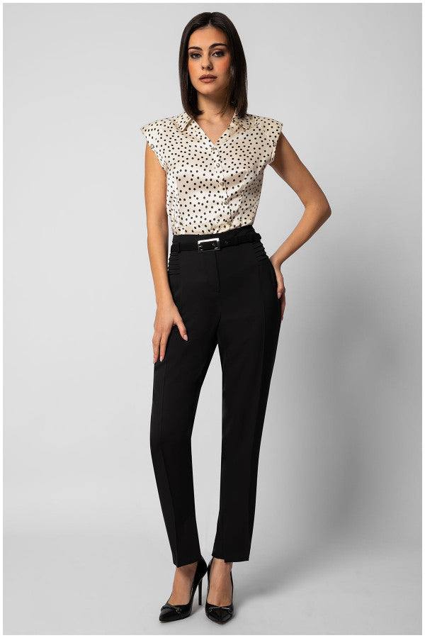 Woman wearing sleeveless satin polka dot elegant blouse with decorative buttons paired with tailored black pants and heels