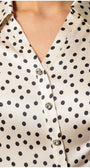 Close-up of Talia satin elegant blouse with black polka dots and decorative diagonal buttons on ivory fabric