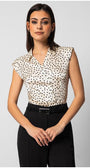 Woman wearing sleeveless satin elegant blouse with black polka dots and decorative buttons paired with black tailored pants