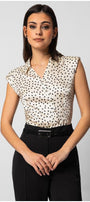 Woman wearing sleeveless satin elegant blouse with black polka dots and decorative buttons paired with black tailored pants