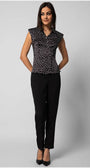 Woman wearing a sleeveless black satin elegant blouse with white polka dots and decorative diagonal buttons paired with tailored black pants.