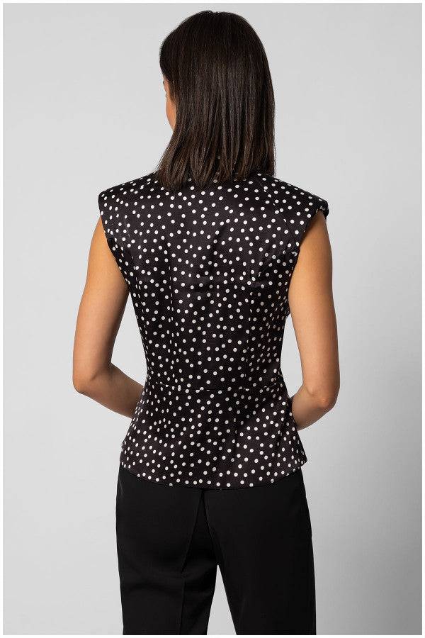 Back view of sleeveless black satin elegant blouse with white polka dots and structured shoulders on model