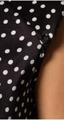 Close-up of black satin sleeveless elegant blouse with white polka dots and decorative diagonal button detail