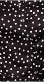 Close-up of black satin elegant blouse with white polka dots and decorative diagonal buttons on smooth fabric.